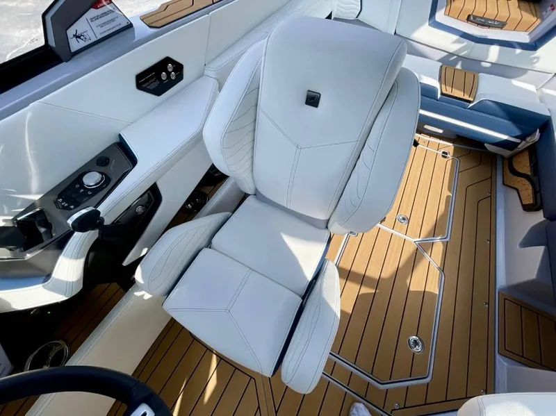 Slide: The Image of 2025 Nautique G23 interior with white captain's chair and teak flooring. - 14