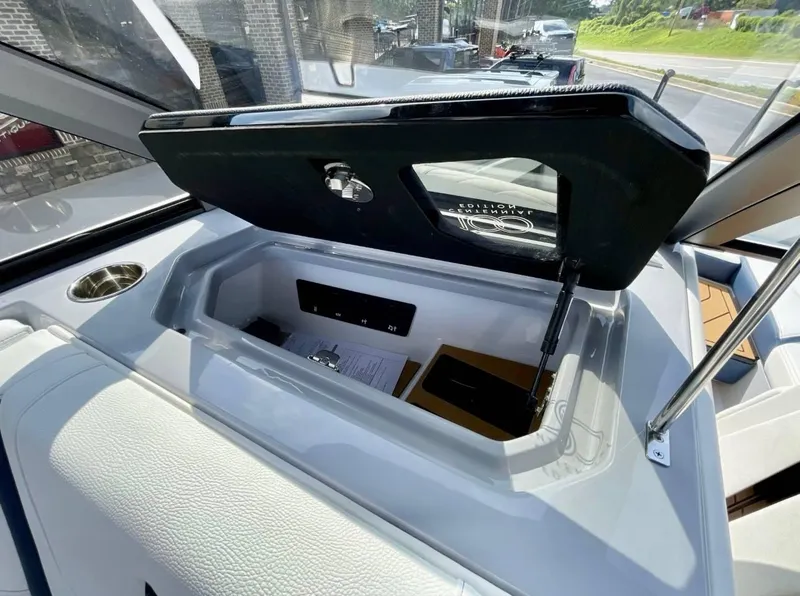 Slide: The Image of 2025 Nautique G23 boat storage compartment with open lid, showcasing interior details. - 15