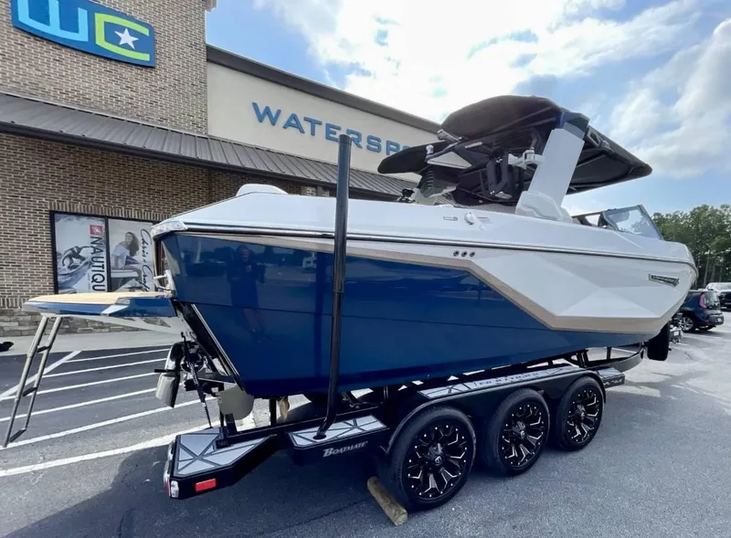 Slide: The Image of 2025 Nautique G23 boat on trailer outside Watersports store. - 6