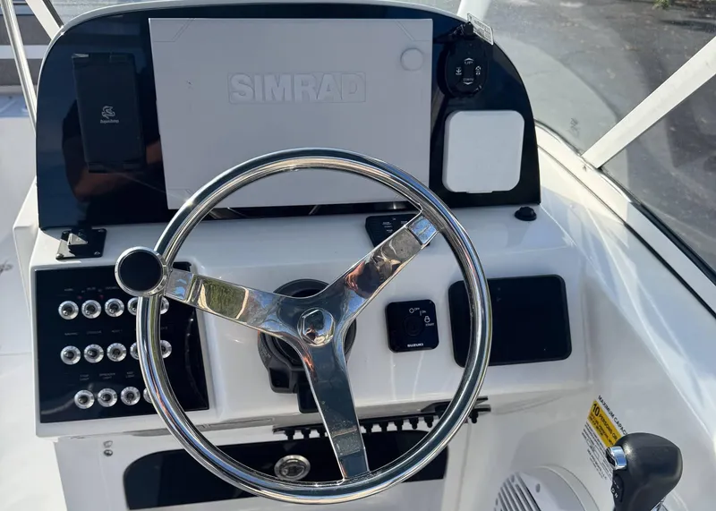Slide: The Image of 2023 Sea Pro 240 DC boat dashboard with steering wheel and Simrad display. - 15
