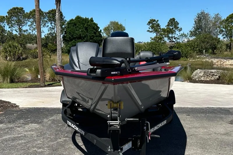 Slide: The Image of 2025 Tracker Pro Team 175 boat on trailer, parked outdoors, with trees in the background. - 2