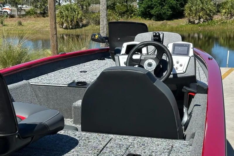 Slide: The Image of 2025 Tracker Pro Team 175 boat interior with steering wheel and dashboard near a lake. - 4