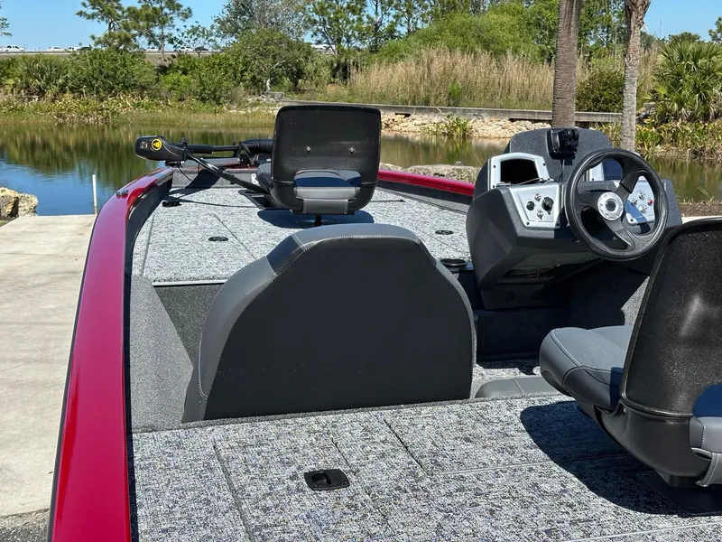 Slide: The Image of 2025 Tracker Pro Team 175 boat with seating and steering wheel, near a serene lake. - 5