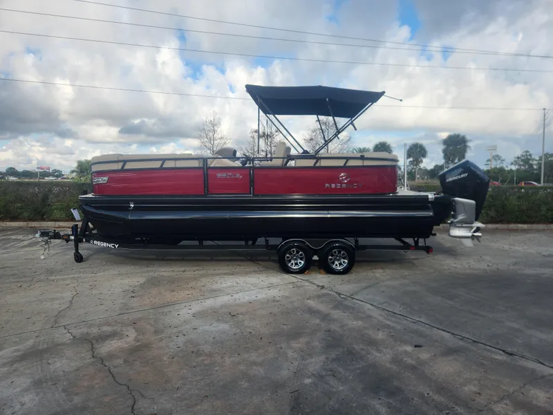 The Image of 2025 Regency 230 LE3 pontoon boat with canopy on trailer, parked outdoors. - 0