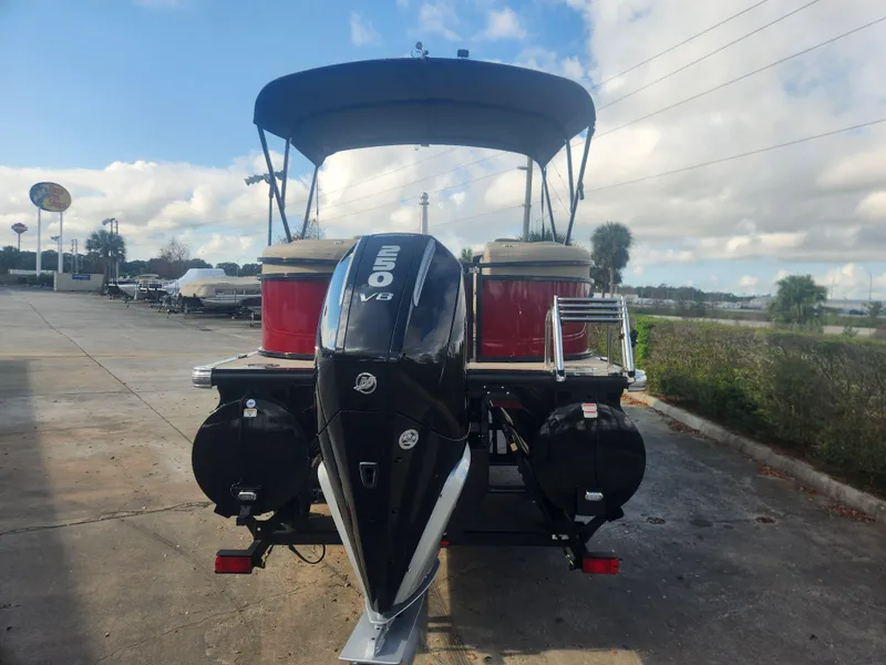 Slide: The Image of 2025 Regency 230 LE3 pontoon boat with powerful outboard motor, parked outdoors. - 2