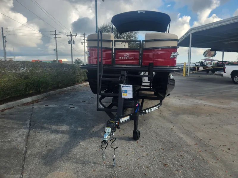Slide: The Image of 2025 Regency 230 LE3 pontoon boat on trailer, parked outdoors under cloudy sky. - 3