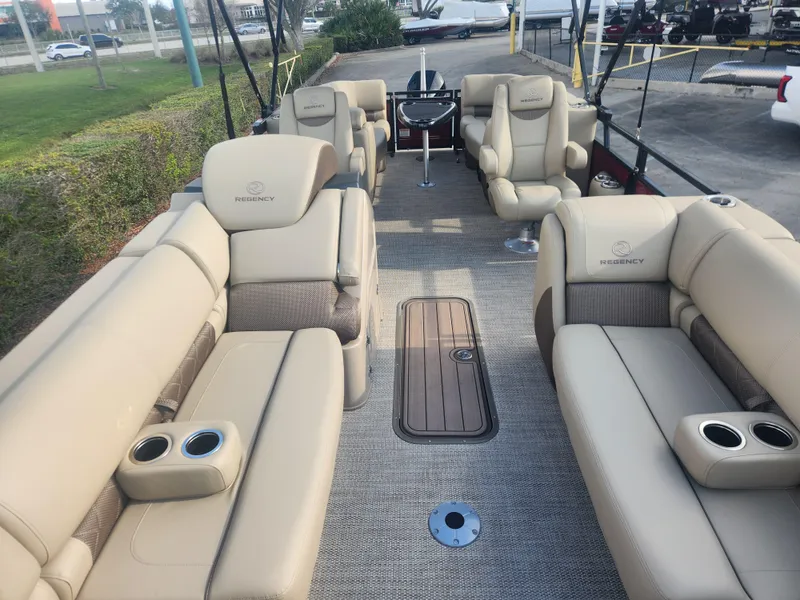 Slide: The Image of 2025 Regency 230 LE3 pontoon boat interior with beige seating and cup holders. - 5