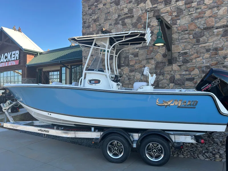 Slide: The Image of 2025 Mako 214 CC boat on trailer, parked outside a stone building. - 0
