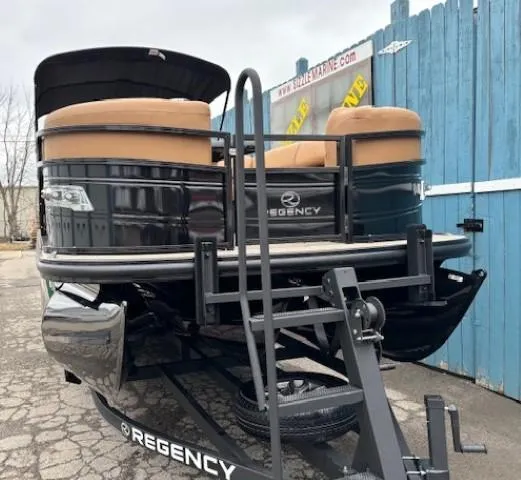 Slide: The Image of 2024 Regency 250 LE3 Sport pontoon boat on trailer, parked near blue fence. - 2