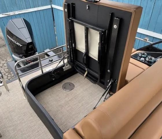 Slide: The Image of 2024 Regency 250 LE3 Sport boat interior with Mercury engine, featuring tan seating and storage area. - 30
