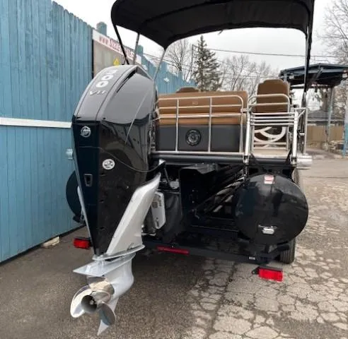 Slide: The Image of 2024 Regency 250 LE3 Sport boat with powerful outboard motor, parked near blue fence. - 5