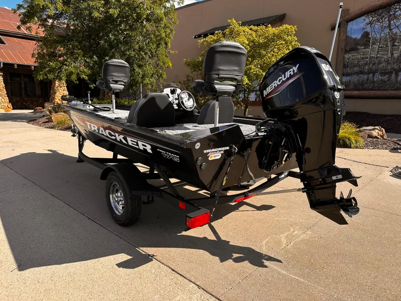 Slide: The Image of 2025 Tracker Pro Team 175 boat with Mercury engine, parked outdoors on a sunny day. - 2