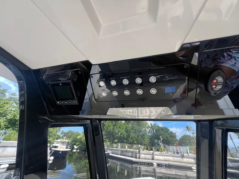 Slide: The Image of 2025 Scout 261 XSS boat control panel with various switches and display, docked by the water. - 12