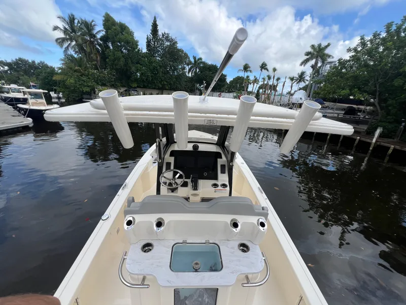 Slide: The Image of 2025 Scout 261 XSS boat with fishing rod holders, docked on a calm waterway. - 14