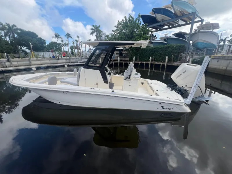 Slide: The Image of 2025 Scout 261 XSS boat docked on calm water under a cloudy sky. - 2