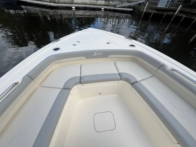 Slide: The Image of 2025 Scout 261 XSS boat interior with cushioned seating, docked by the water. - 5