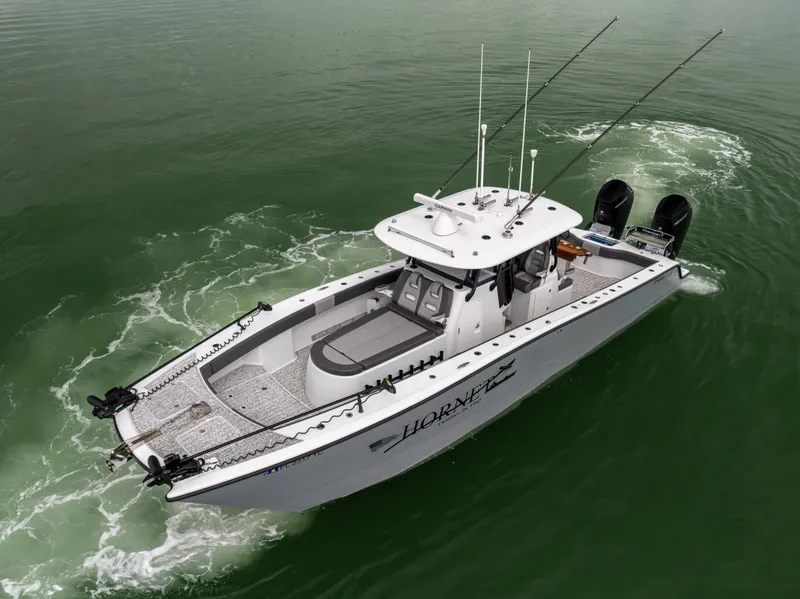 Slide: The Image of 2022 Freeman 37 VH boat cruising on green water, equipped with fishing rods and dual engines. - 14