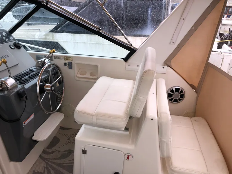 Slide: The Image of 2000 Tiara Yachts 3100 Open helm with white seating and steering wheel. - 7