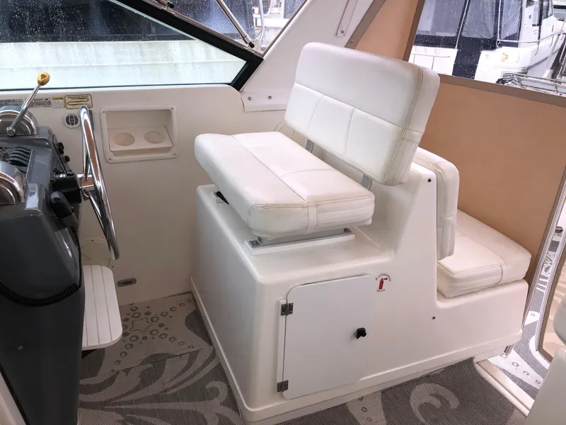 Slide: The Image of 2000 Tiara Yachts 3100 Open helm with white seating and steering wheel. - 8