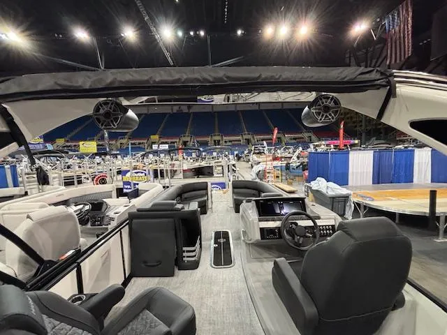 Slide: The Image of 2025 Harris Grand Mariner 250 interior at a boat show, showcasing luxury seating and modern controls. - 32