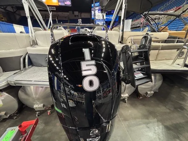 Slide: The Image of 2025 Harris Sunliner 230 CWDH pontoon boat with 150 horsepower engine displayed indoors. - 1