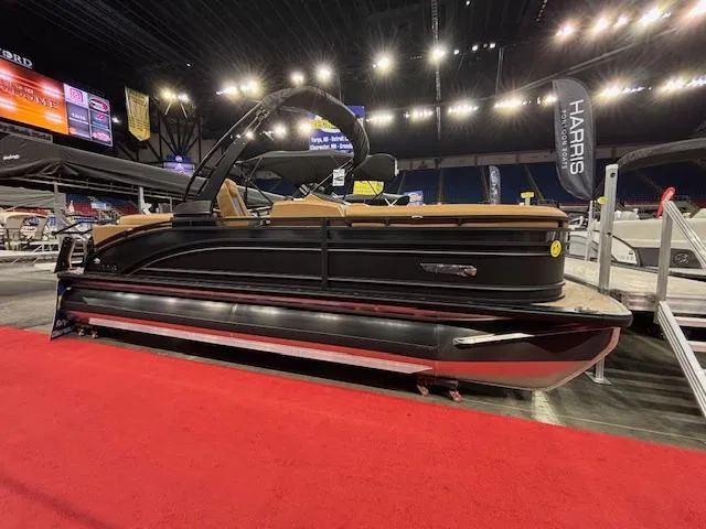 Slide: The Image of 2025 Harris Solstice 230 pontoon boat displayed indoors on red carpet. - 1