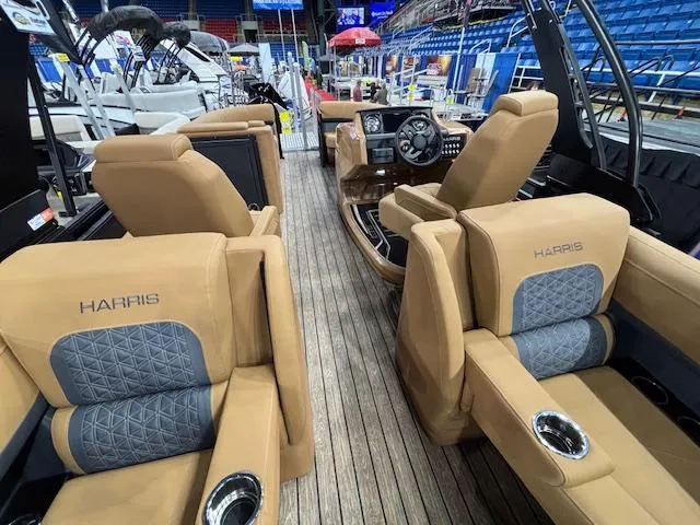 Slide: The Image of 2025 Harris Solstice 230 boat interior with tan and gray seating, wood flooring, and steering console. - 13