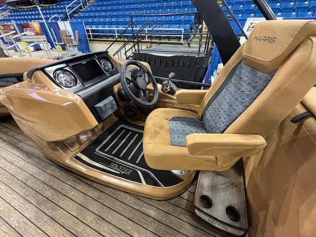 Slide: The Image of 2025 Harris Solstice 230 boat interior with tan and gray captain's chair, steering wheel, and dashboard. - 15