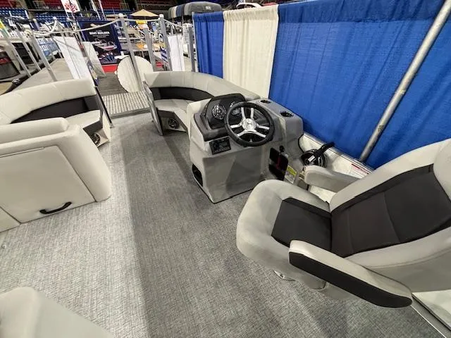 Slide: The Image of 2025 Harris Cruiser 210 SL interior with modern seating and steering console at a boat show. - 10