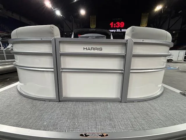 Slide: The Image of 2025 Harris Cruiser 210 SL pontoon boat displayed indoors with modern seating. - 2