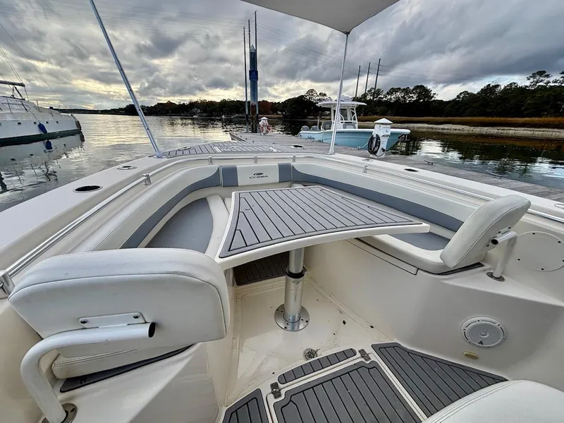 Slide: The Image of 2019 Cobia 301 Center Console boat with seating and table, docked by a serene waterfront. - 15