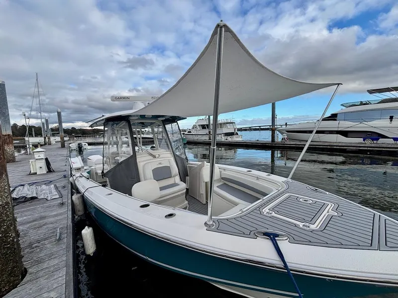 Slide: The Image of 2019 Cobia 301 Center Console boat docked with canopy, calm waters, and cloudy sky. - 16