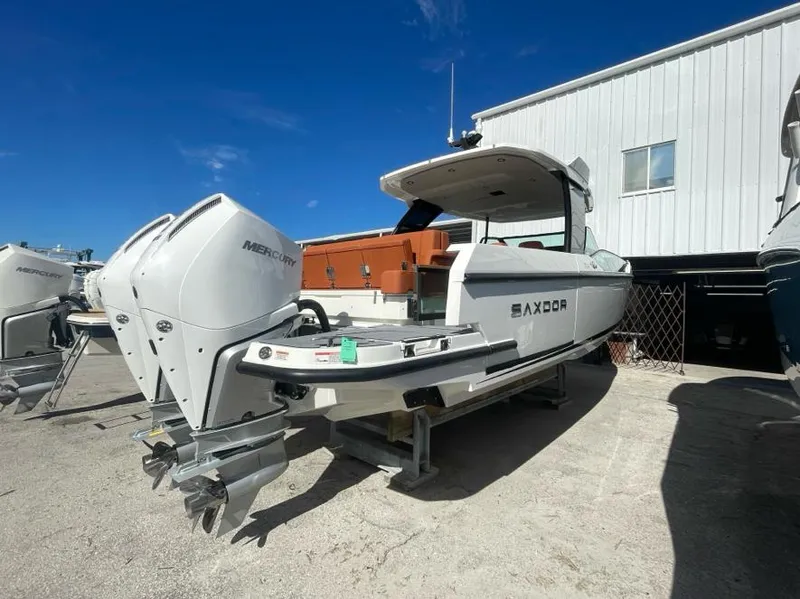 The Image of 2025 Saxdor 320 GTO boat with dual Mercury engines, parked outdoors under a clear blue sky. - 1