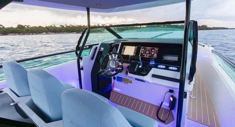 Slide: The Image of 2025 Saxdor 320 GTO boat interior with modern dashboard and steering, overlooking serene waters. - 14