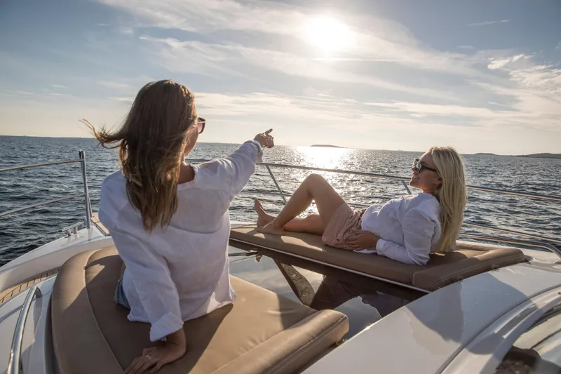 Slide: The Image of Two people relaxing on a 2025 Nimbus 405 Flybridge yacht at sunset. - 15