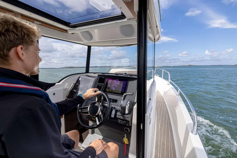 Slide: The Image of Man steering 2025 Nimbus Commuter 8 boat on open water. - 14