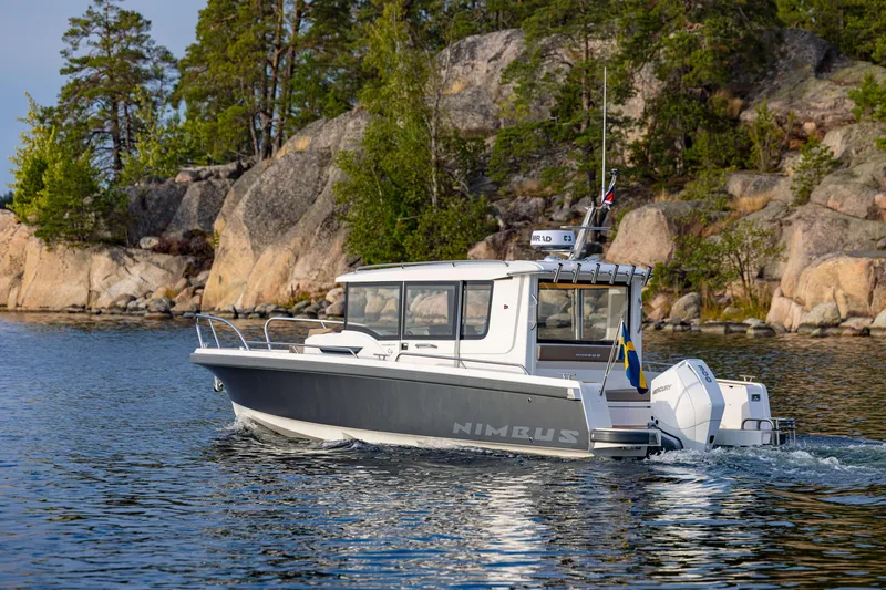 Slide: The Image of Nimbus Commuter 9 boat cruising near rocky shoreline, 2025 model. - 26