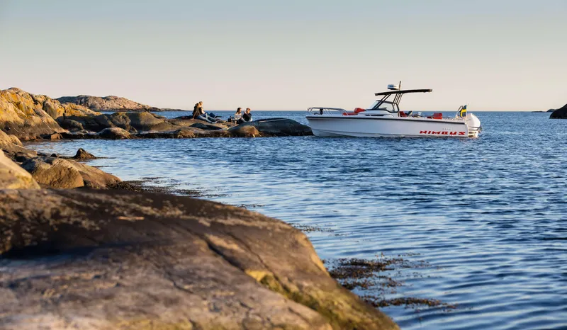 Slide: The Image of 2025 Nimbus Tender 8 boat near rocky shoreline at sunset. - 16