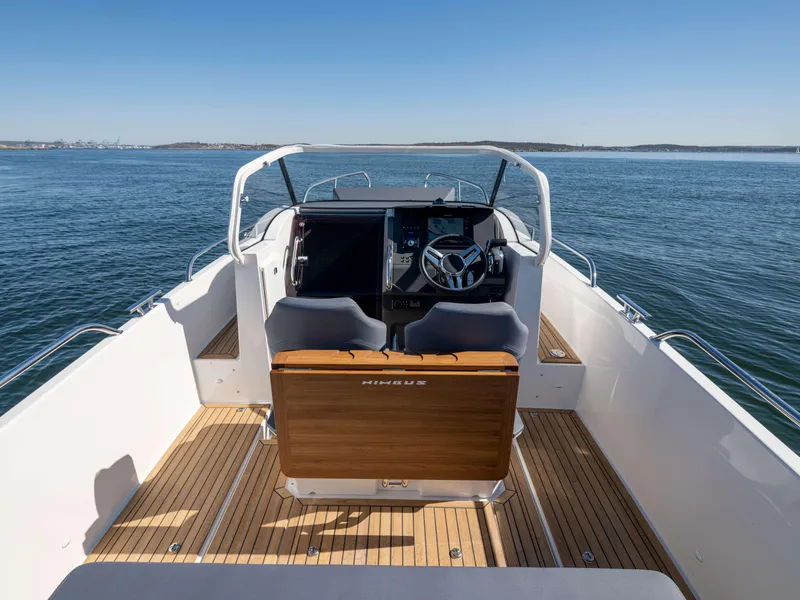 Slide: The Image of 2025 Nimbus Tender 8 boat interior with wooden deck, steering console, and open water view. - 17