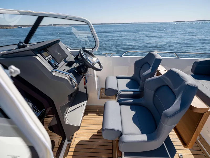 Slide: The Image of Interior of 2025 Nimbus Tender 8 boat with modern steering and seating, overlooking the ocean. - 20
