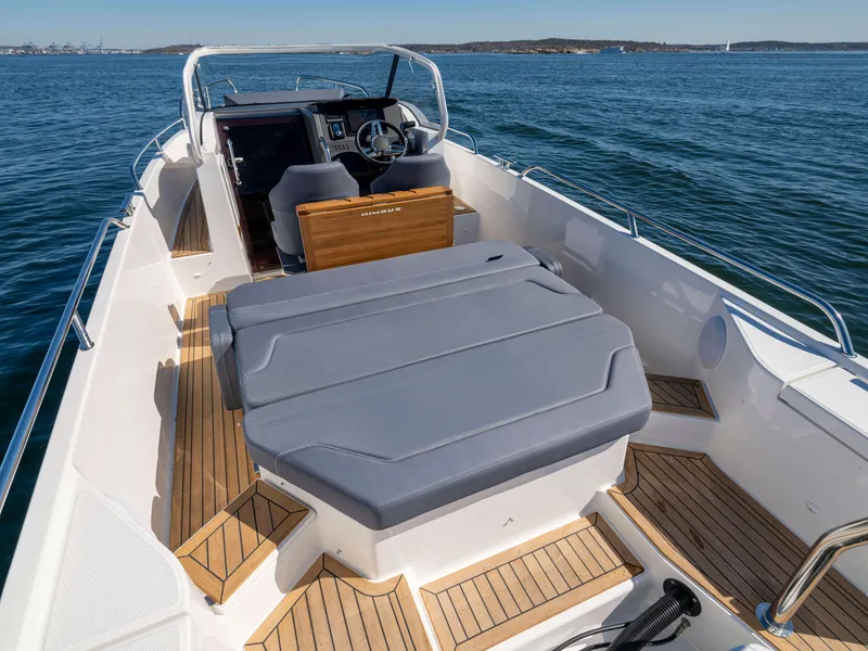 Slide: The Image of 2025 Nimbus Tender 8 boat interior with cushioned seating and wooden deck, on calm water. - 22