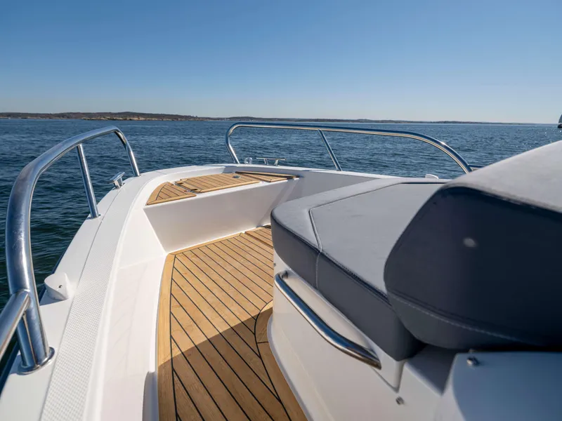 Slide: The Image of 2025 Nimbus Tender 8 boat with teak deck and cushioned seating on open water. - 27