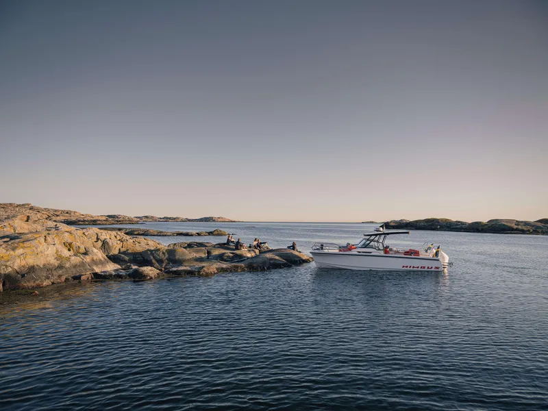 Slide: The Image of 2025 Nimbus Tender 8 boat anchored near rocky shoreline under clear sky. - 3