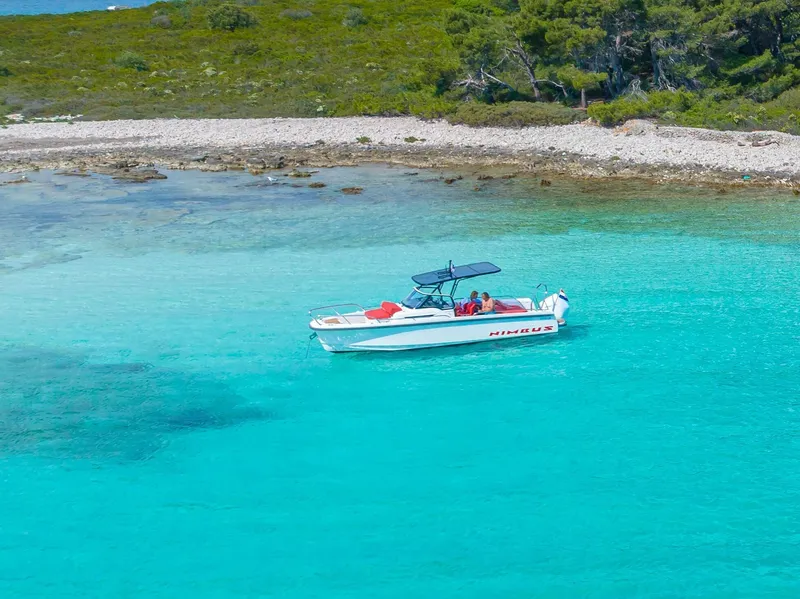 Slide: The Image of Nimbus Tender 8 boat in turquoise water near a rocky shoreline, 2025 model. - 35