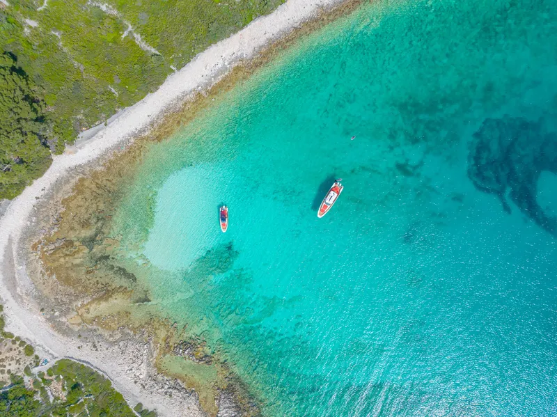 Slide: The Image of Aerial view of two Nimbus Tender 8 boats in clear turquoise water near a rocky shoreline. - 36