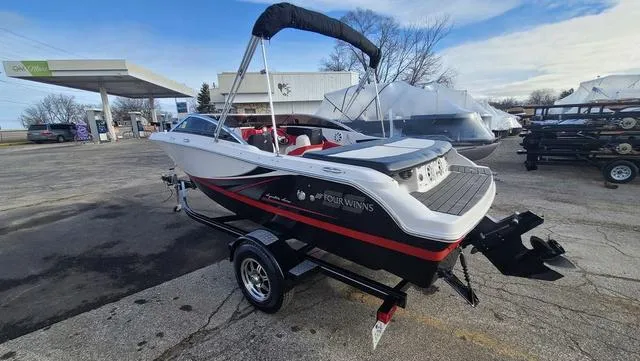 Slide: The Image of 2016 Four Winns H 180 SS boat on trailer, parked outdoors near a gas station. - 6