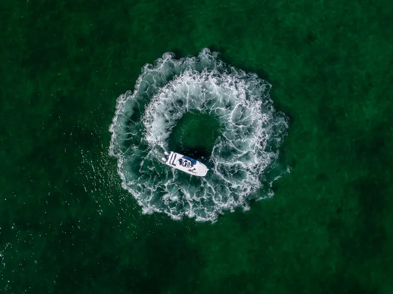 Slide: The Image of Aerial view of Freeman 28 boat creating circular wake in green water, 2025 model. - 18