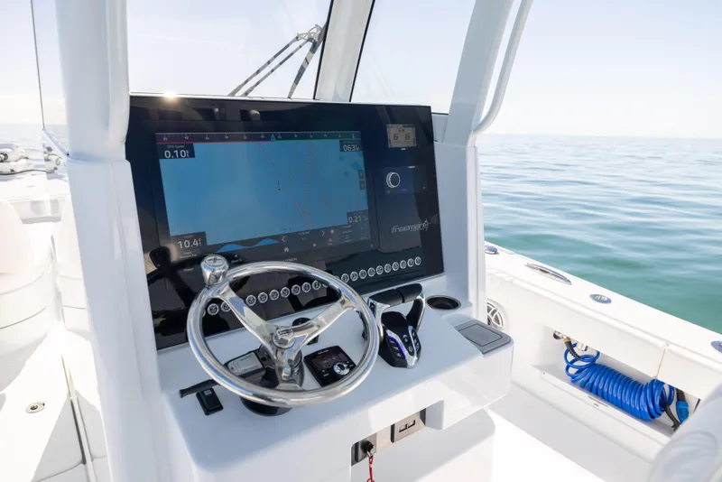 Slide: The Image of Freeman 28 boat dashboard with navigation screen, steering wheel, and ocean view, 2025 model. - 39