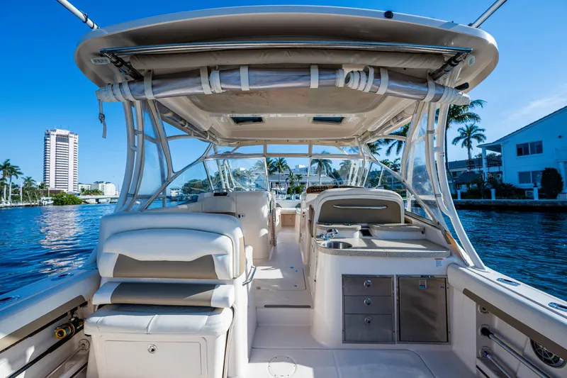 Slide: The Image of 2013 Grady-White 335 boat interior with seating and storage, docked by waterfront homes. - 12