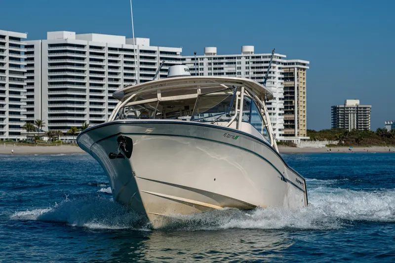 Slide: The Image of 2013 Grady-White 335 boat cruising near modern beachfront buildings. - 26